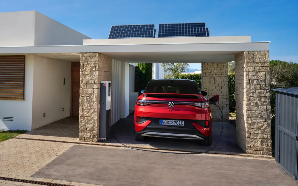 Electric SUV parked in a home carport, plugged into a wall charger