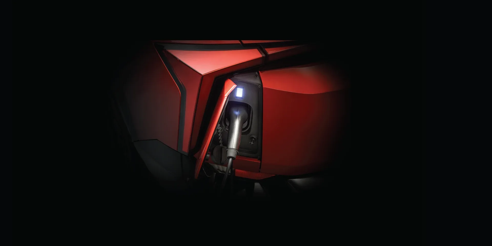 A Mahindra XEV 9e plugged into a fast charger, its charge port lit